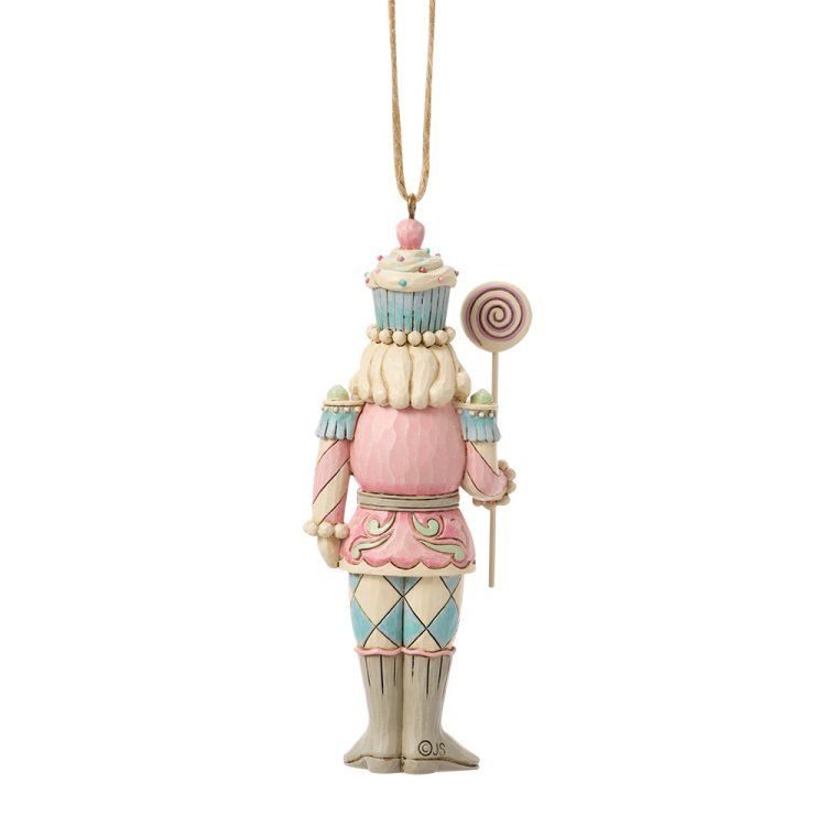 Een notenkrakerornament in roze, blauw en wit, met een lolly in zijn hand.