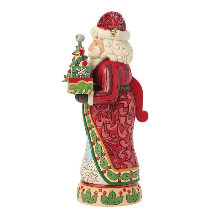 Een kerstmanfiguurtje met een kleine kerstboom en een cadeautje, gekleed in een rood-crème gewaad.