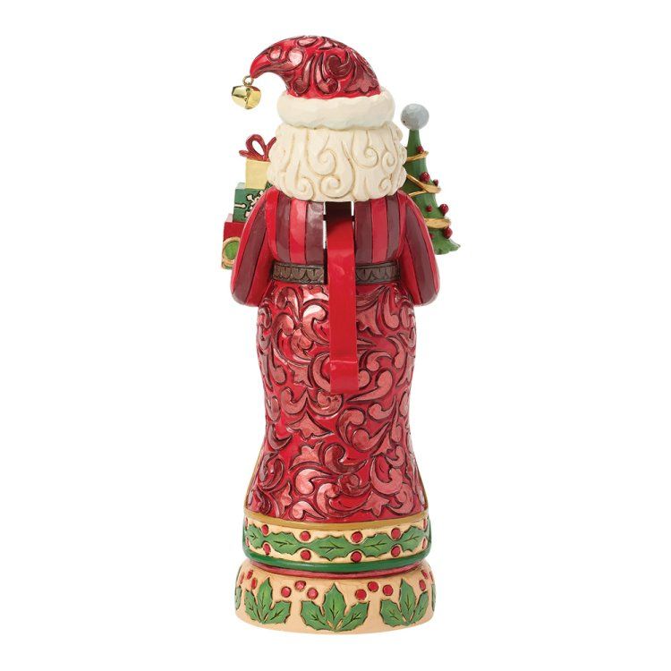 Een notenkraker in de vorm van de Kerstman, gekleed in rood, met cadeautjes en een kerstboom, op een met hulst versierde sokkel.