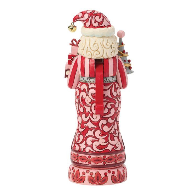 Achteraanzicht van een rood-roze kerstmanfiguurtje dat cadeautjes en een kleine kerstboom vasthoudt.