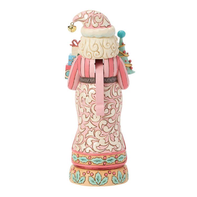 Roze en witte kerstmanfiguur met cadeautjes en kerstboom, staand op een decoratieve sokkel.