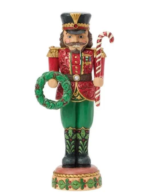 Een notenkrakerfiguur in een rood-groen uniform, met een krans en een zuurstok in de hand.