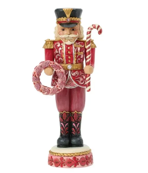 Notenkrakerfiguur in rood uniform met een zuurstok en een krans.