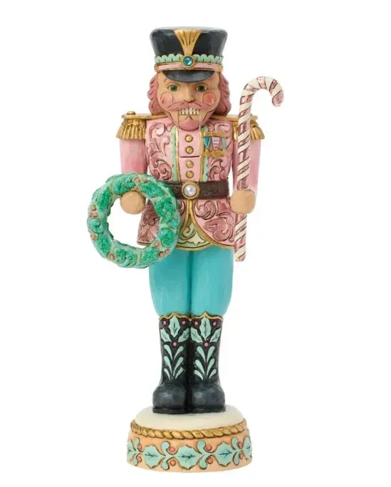 Een notenkrakerbeeld in een roze, blauwe en zwarte outfit, met een krans en een wandelstok.