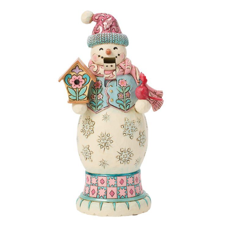 Een sneeuwpopfiguurtje met een roze en blauwe muts, sjaal en vest, die een vogelhuisje vasthoudt.