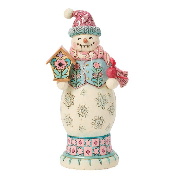 Een sneeuwpopfiguurtje met een roze en blauwe muts, sjaal en vest, die een vogelhuisje vasthoudt.