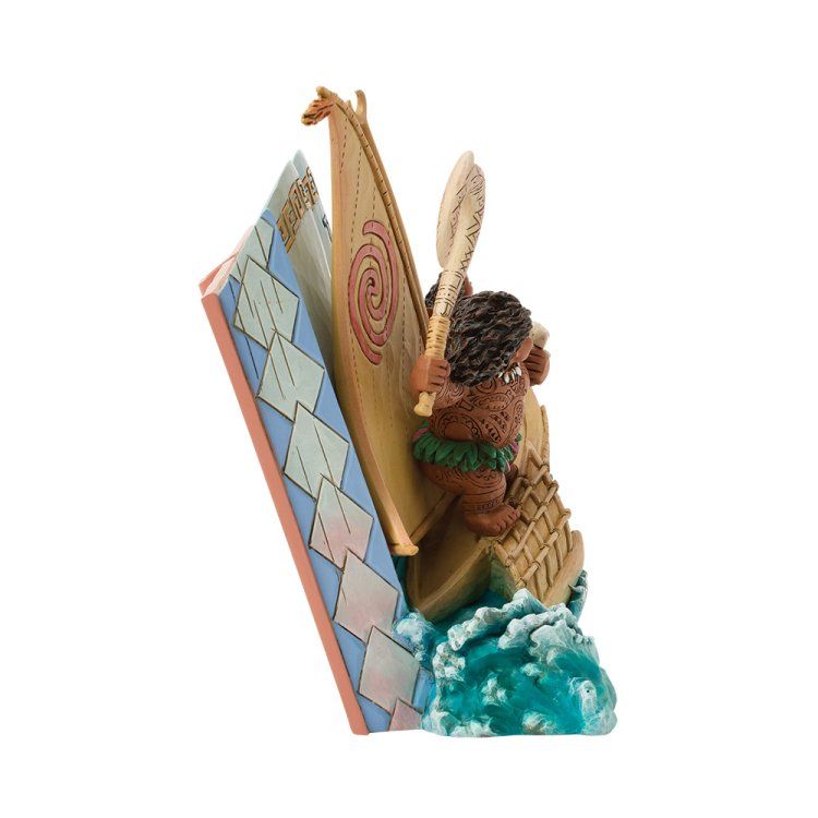 Een Moana-beeldje met kano en Maui, geplaatst op een golvende sokkel, met op de achtergrond een boek.