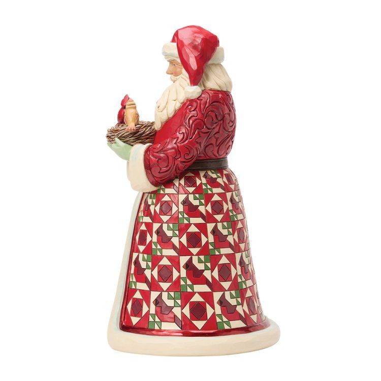 Figuur van de kerstman in een rode jas, met een vogel in zijn hand en een rok met patchworkpatroon.