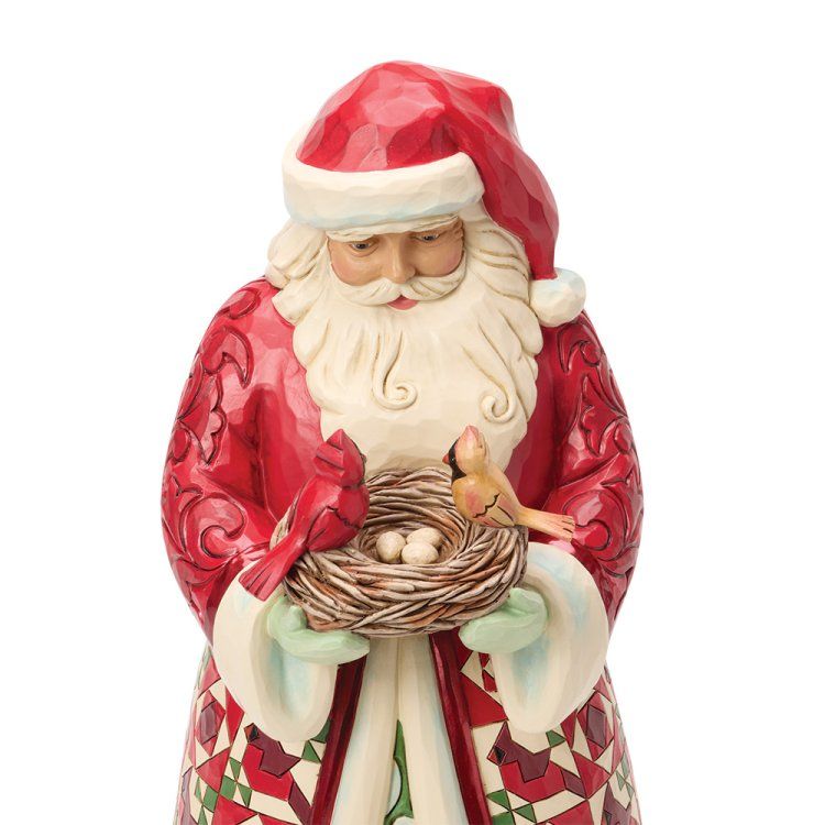 Een kerstmanfiguurtje met een vogelnest met kardinalen en eieren. Rode jas en muts.