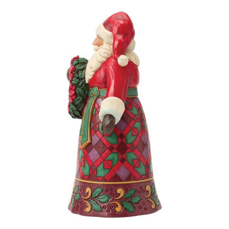 Een kerstmanfiguur met een krans van rode bloemen; hij draagt een rood pak met een rok met patroon.