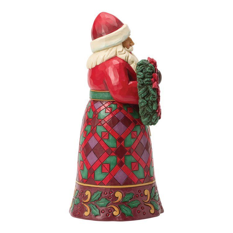 Een kerstmanfiguur in een rode jas met een kerstkrans en een groen-rode rok.