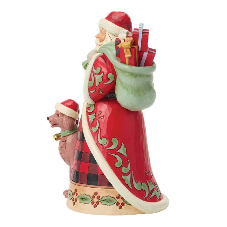 Een kerstmanfiguur met een hond die een kerstmuts draagt; gekleed in rode en groene kleding, met een zak vol cadeaus.