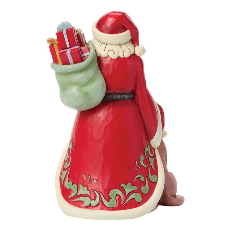 Een kerstmanfiguur, van achteren gezien, met een rode jas met groene bies, een zak met cadeaus en een hondje naast hem.