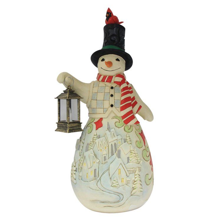 Sneeuwpop met lantaarn, hoed, sjaal en vest aan, met een vogel op de hoed en een dorpsscène op zijn lichaam.