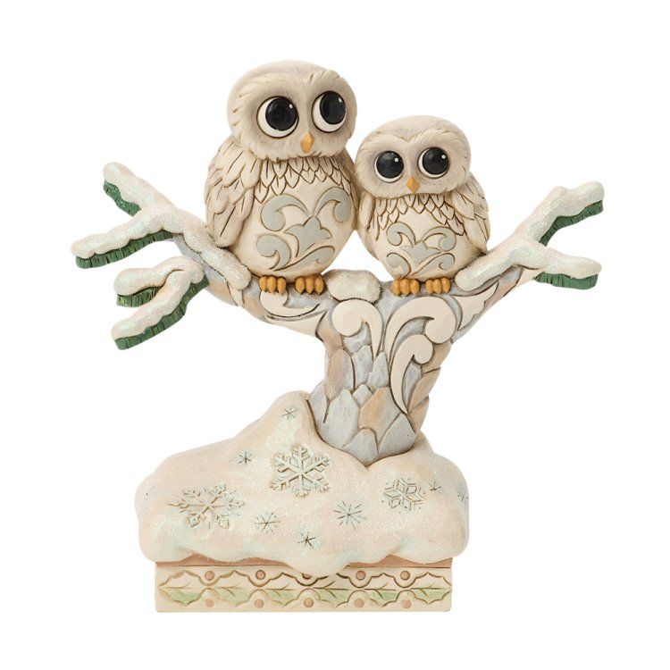 Twee uilenbeeldjes zitten op een besneeuwde tak; met decoratieve houtsnijwerken, grote ogen en winterse kleuren.