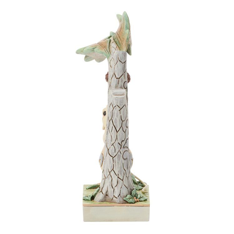 Een uit hout gesneden boomsculptuur met een vogel bovenop en een konijn eronder.