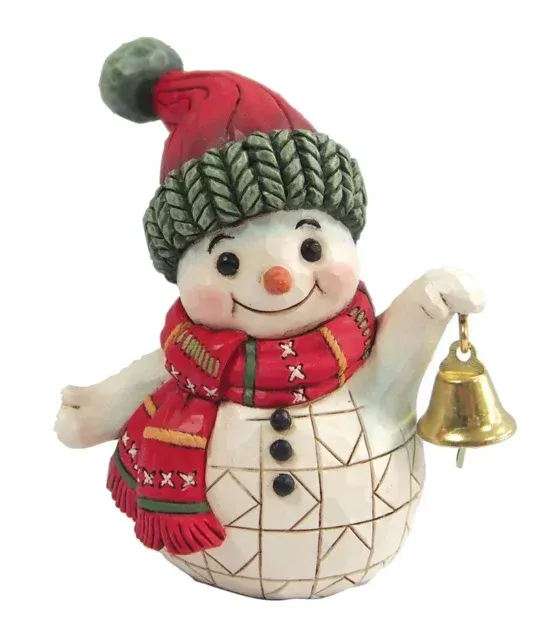 Een sneeuwpopje met een rode muts en sjaal, die een gouden bel vasthoudt.