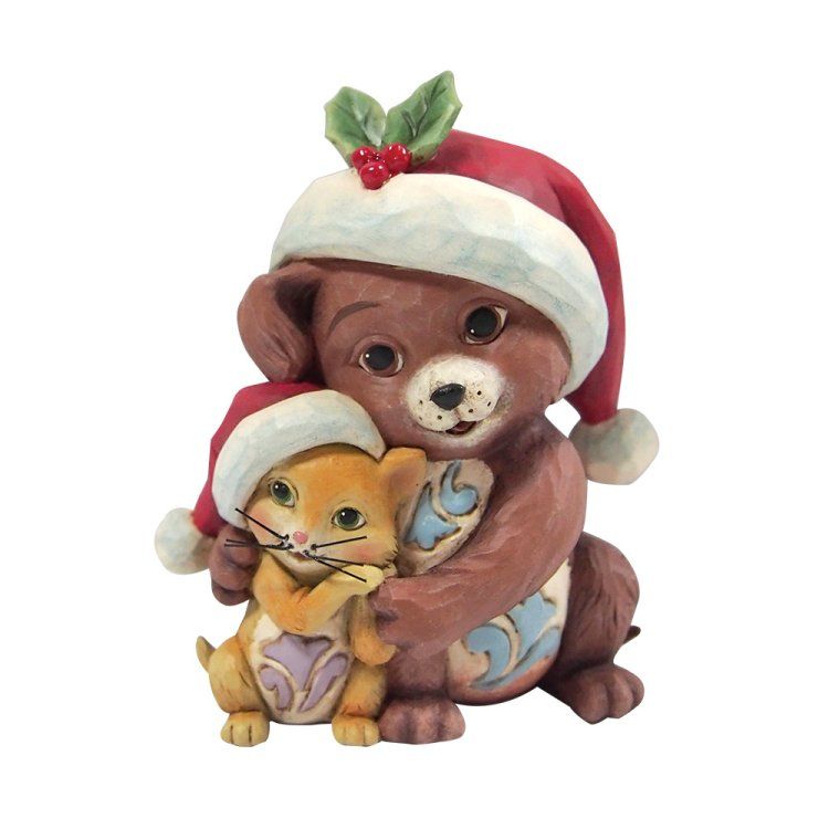Een bruine beer knuffelt een geel katje, beiden dragen een kerstmuts, met hulst op de muts van de beer; een kerstfiguurtje.