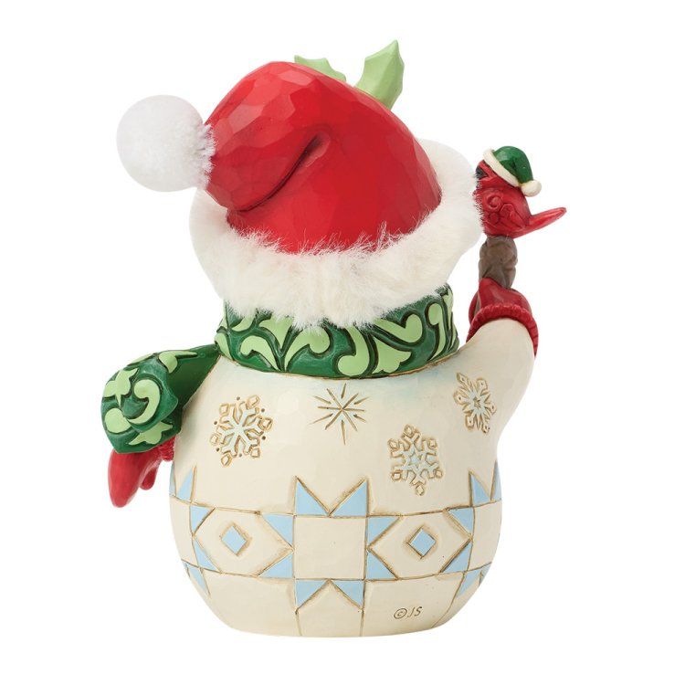 Een sneeuwpop, van achteren gezien, met een kerstmuts en sjaal op en een vogel in zijn handen.