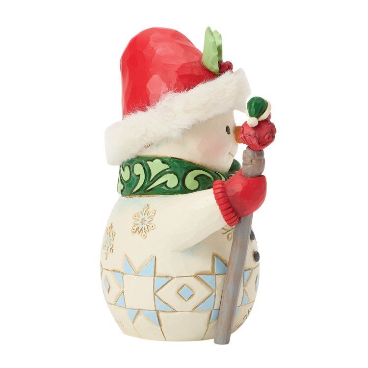 Een sneeuwpopfiguur met een rode muts en een groene sjaal, die een staf met een vogel vasthoudt.