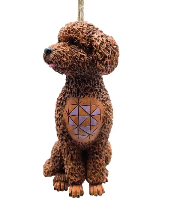 Een bruin poedelornament met een geometrisch patroon op de borst, hangend aan een touwlus.