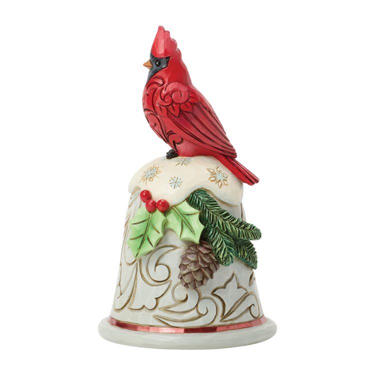 Een rode kardinaal zit bovenop een feestelijk belvormig ornament met hulst, dennenappels en sierlijke krullen.