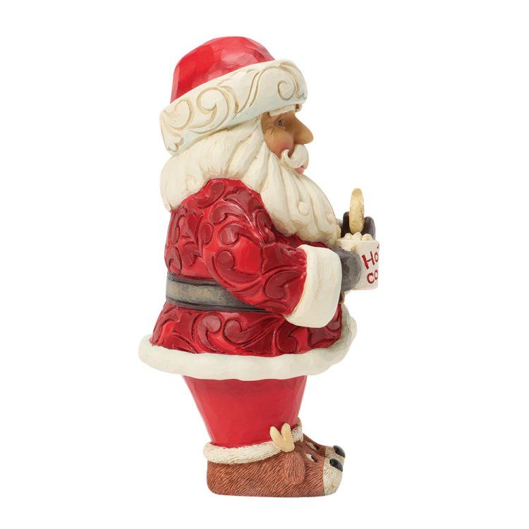 Zijaanzicht van een kerstmanfiguur in rood pak, met een mok 