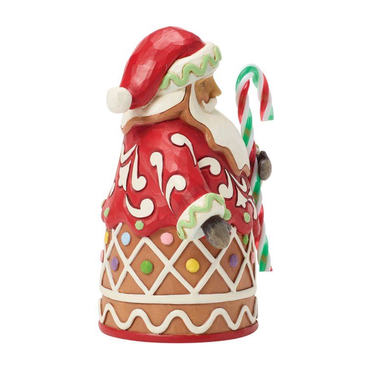Peperkoekfiguurtje van de kerstman met een zuurstok. Rood en wit met groene accenten en pastelkleurige snoepjes.