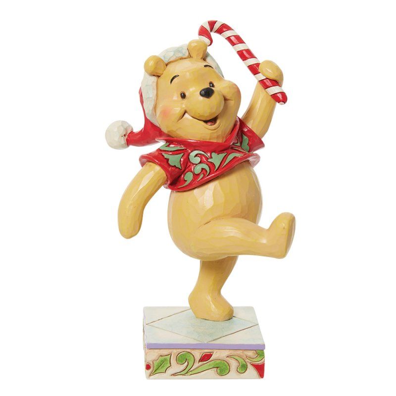 Een Winnie de Pooh-figuurtje met een kerstmuts op, die een zuurstok vasthoudt en op een doos danst.