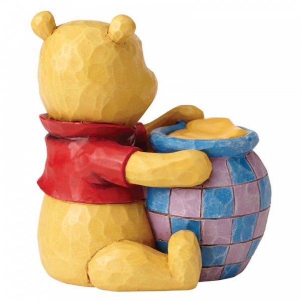 Winnie de Pooh-figuurtje met honingpot, gele beer, rood shirt, zittend en lachend.