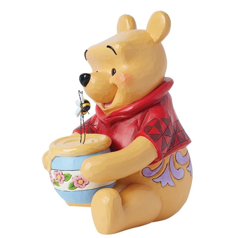 Winnie de Poeh-figuurtje met honingpot, bij en rood shirt.