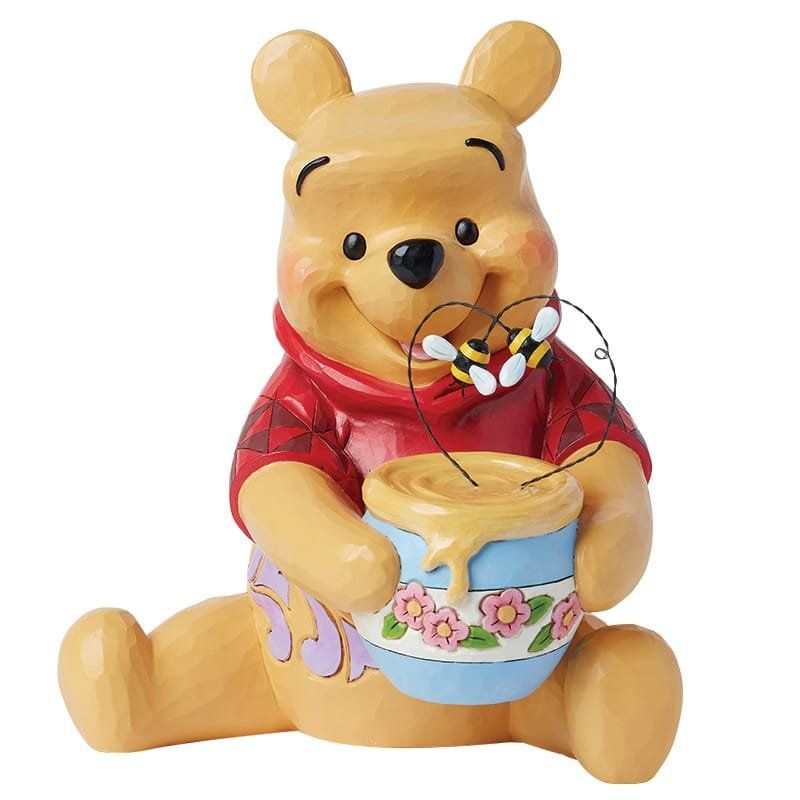 Winnie de Pooh-figuurtje met honingpot en bijen, lachend. Geel, rood, blauw en roze.