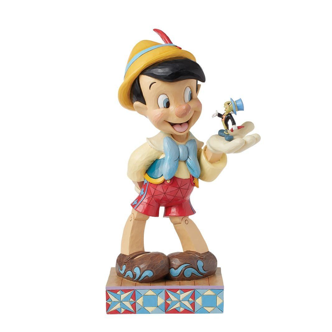 Een Pinocchio-beeldje dat Japie Krekel vasthoudt, lachend, op een versierde sokkel.