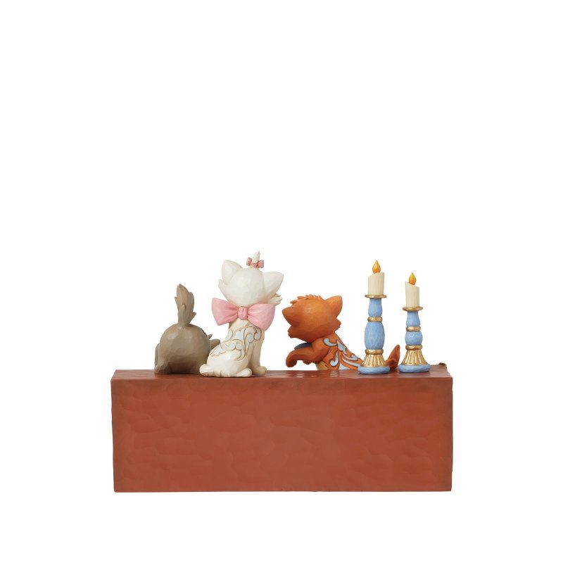 Drie beeldjes van kittens uit Aristocats op een decoratieve piano; oranje, wit en grijs.