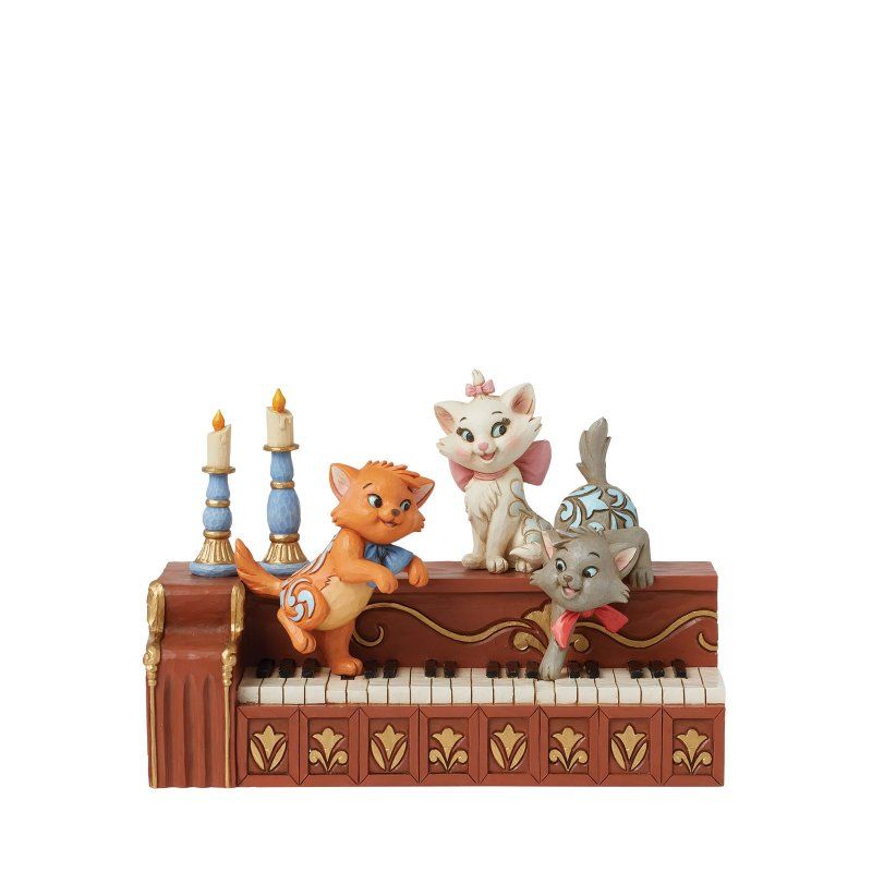 Drie beeldjes van kittens uit Aristocats op een decoratieve piano; oranje, wit en grijs.