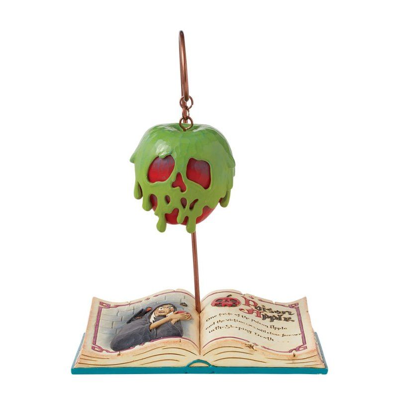 Een ornament in de vorm van een vergiftigde appel op een standaard boven een opengelegd prentenboek met een tekening en tekst.