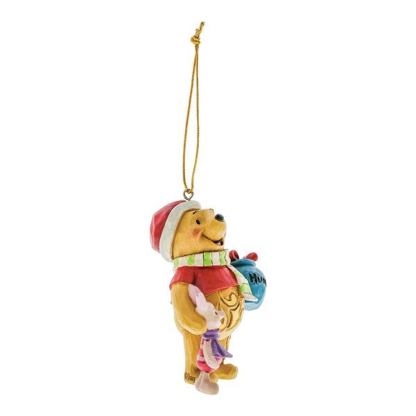 Een kerstornament van Winnie de Poeh, die Knorretje en een blauwe cadeautas vasthoudt en een kerstmuts draagt.