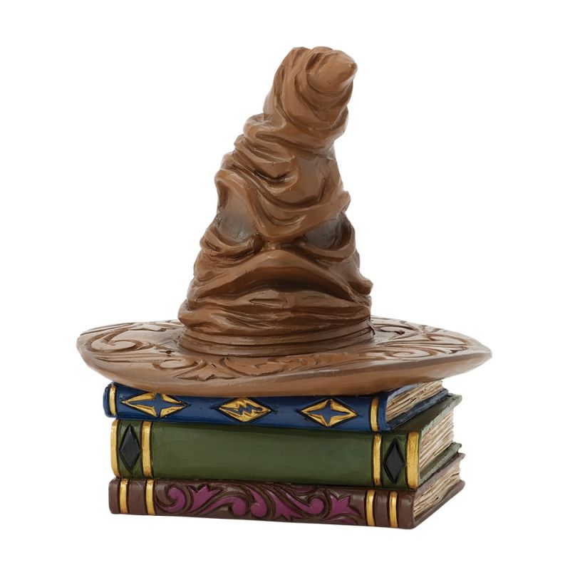 Een beeldje van de Sorteerhoed op een stapel boeken, in bruin-gouden kleuren.