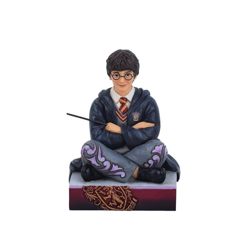 Een Harry Potter-figuurtje dat op een boek zit en een toverstaf vasthoudt.