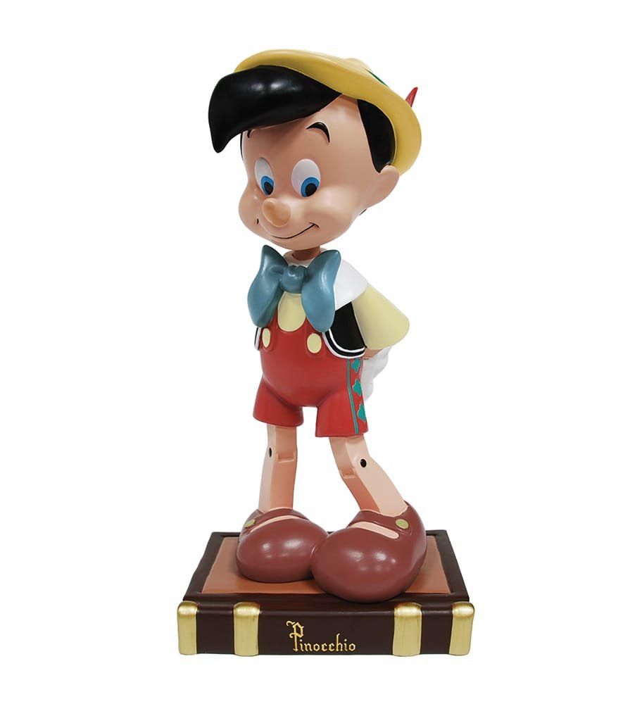 Een Pinocchio-figuurtje met een blauwe vlinderdas, rode korte broek en gele hoed, staand op een doos.