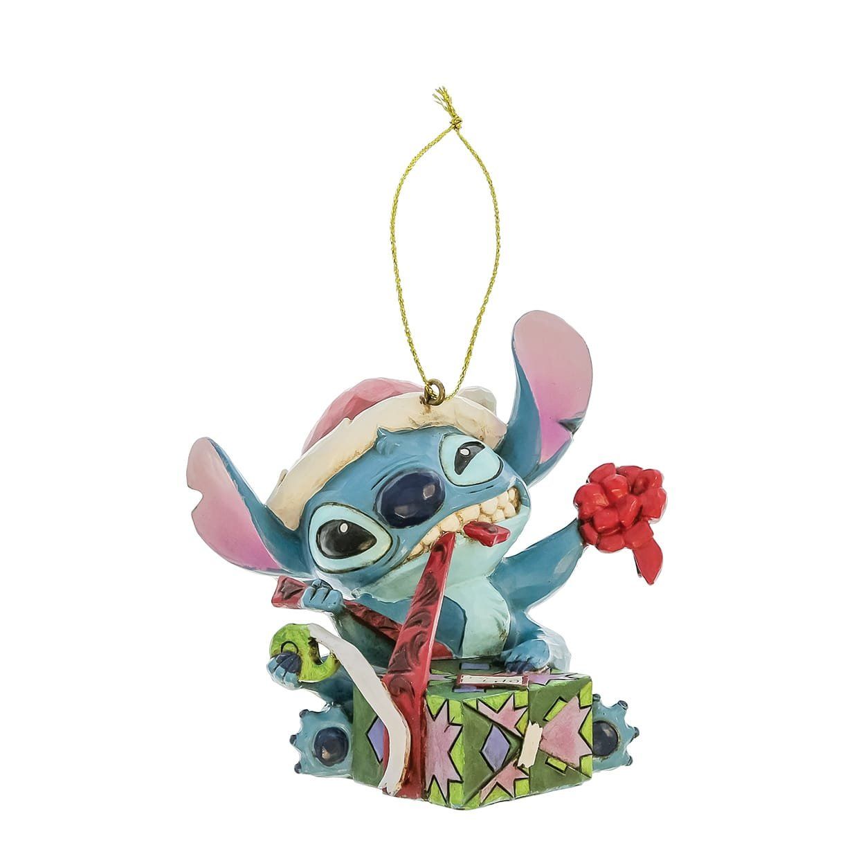 Een kerstornament van Stitch die een kerstmuts draagt en een cadeautje uitpakt; in de kleuren blauw, roze en rood.