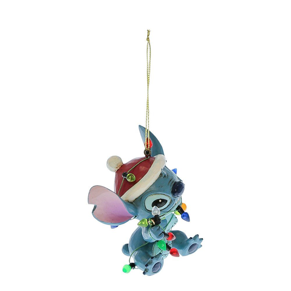 Een kerstornament van Stitch met een kerstmuts op, omwikkeld met kleurrijke lichtslingers, hangt eraan.