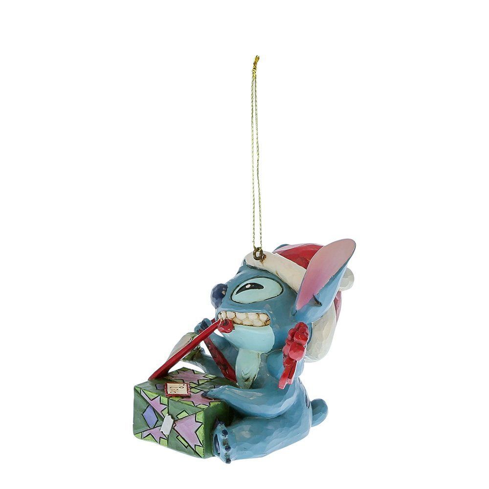 Een kerstornament van Stitch met een kerstmuts op, een tandenborstel in zijn hand en een cadeautje ernaast.