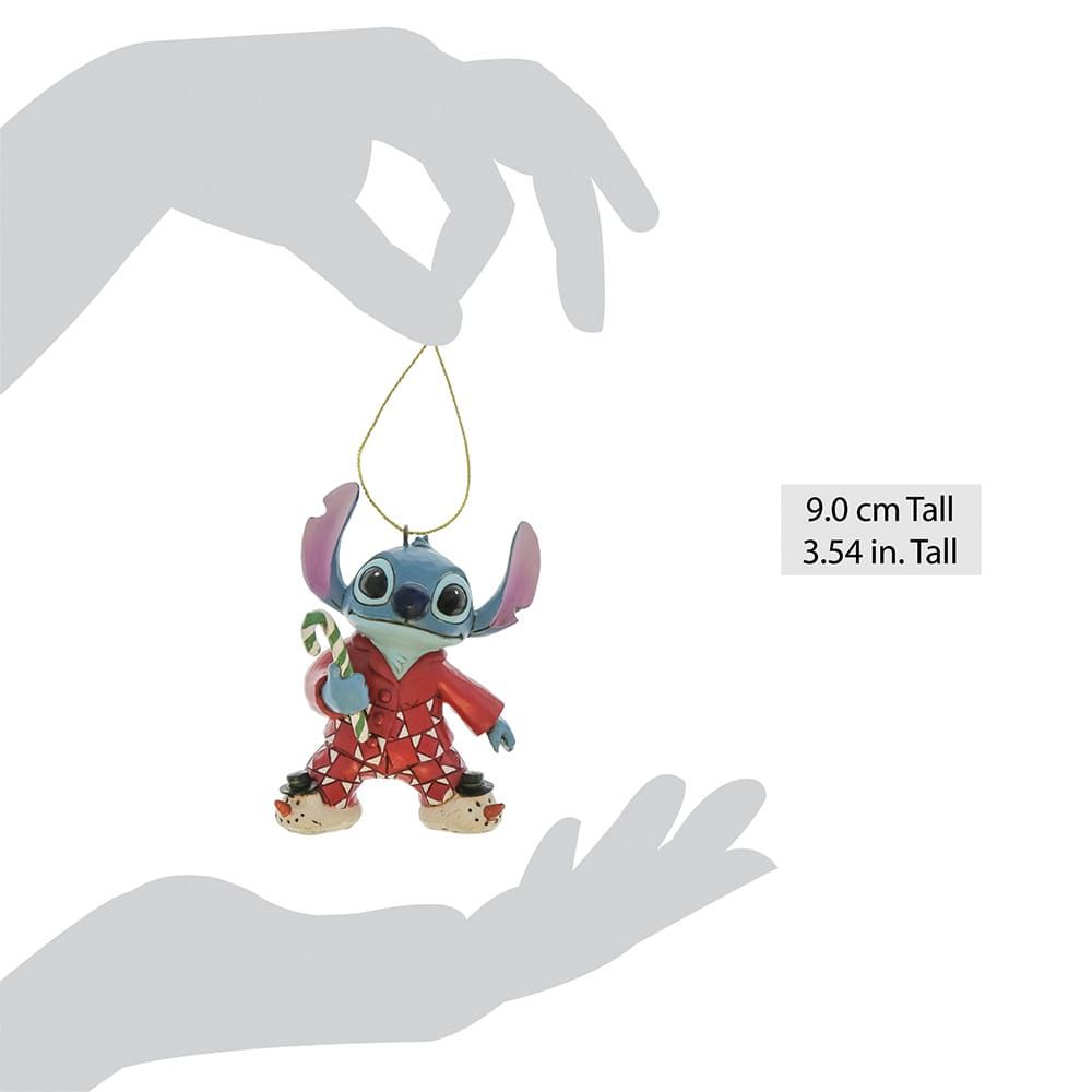 Stitch tekent een kerstornament in een rode pyjama met een zuurstok in zijn handen.
