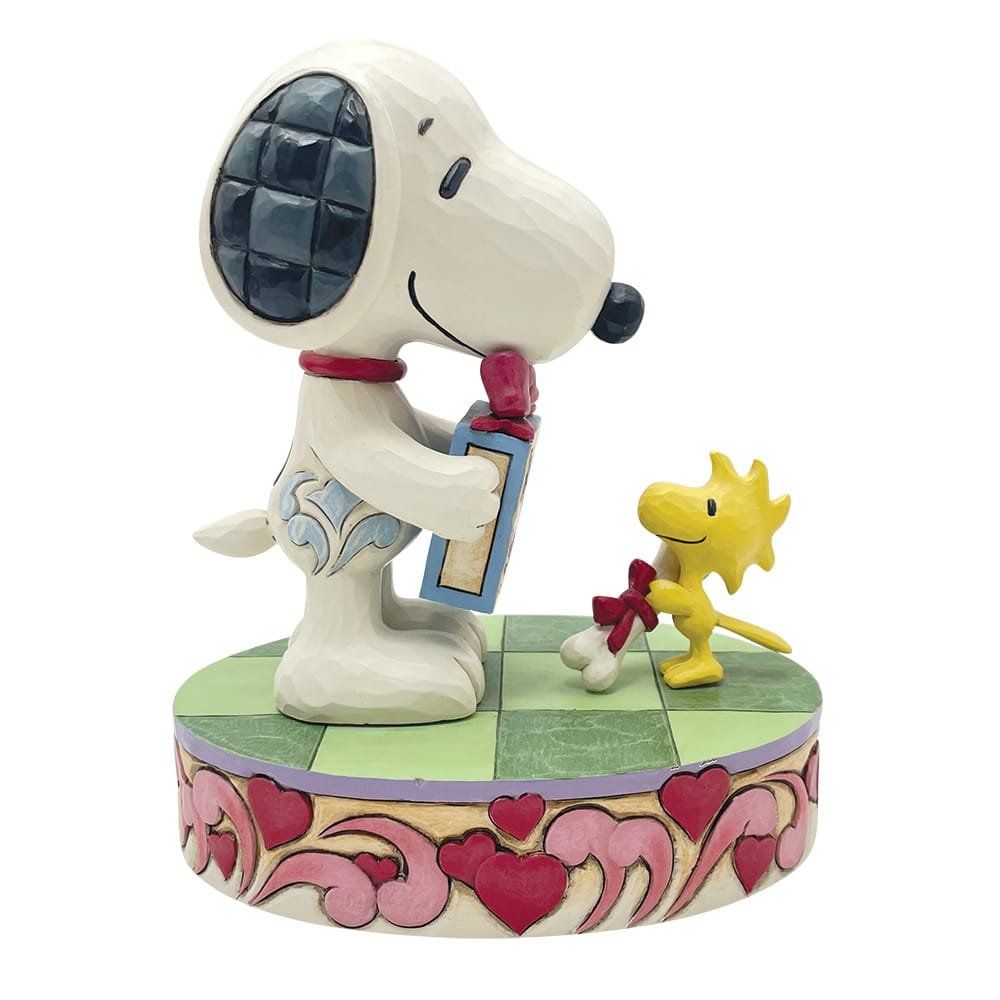 Snoopy en Woodstock beeldje met cadeautje op een voetstuk met hartjespatroon. Snoopy lacht, Woodstock houdt een strik vast.