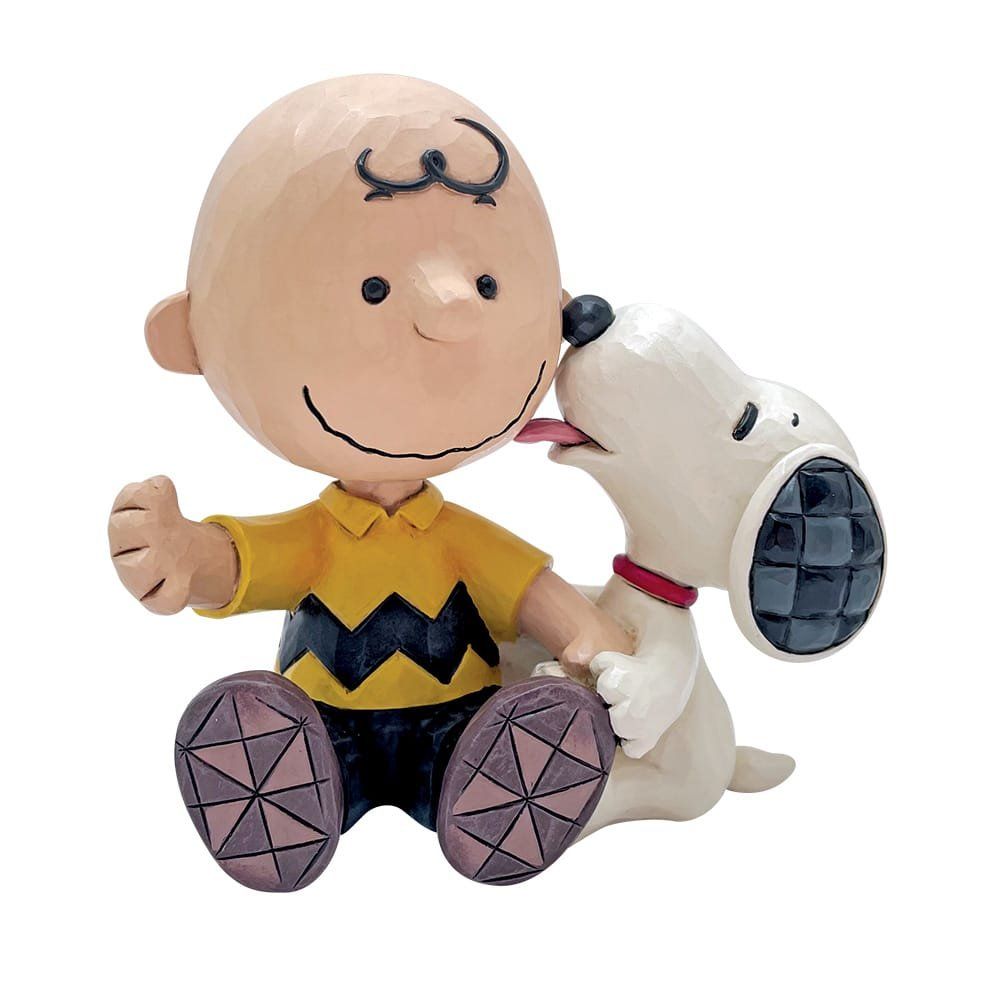 Charlie Brown glimlacht terwijl Snoopy zijn wang likt; het zijn allebei witte beeldjes.