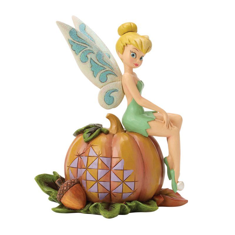 Een Tinkerbell-feeënfiguurtje dat op een pompoen zit met een eikel; in de kleuren groen, oranje en blauw.