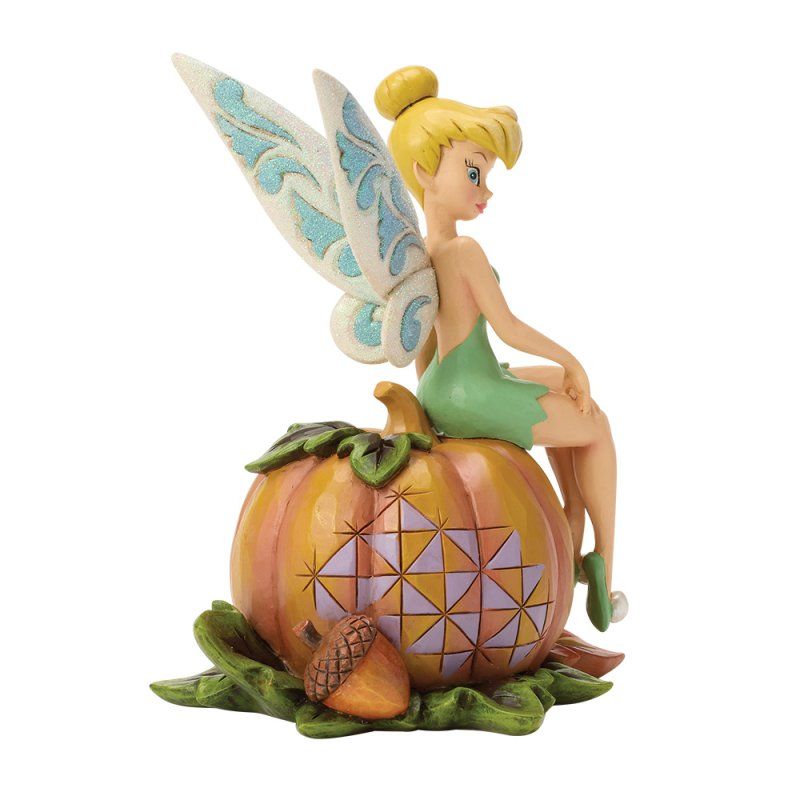 Een figuurtje van Tinkerbell zit op een uitgeholde pompoen met herfstbladeren en een eikel.
