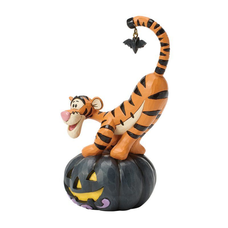 Tigger op een uitgeholde Halloweenpompoen. De oranje tijger reikt naar een vleermuisbedeltje dat aan zijn gestreepte staart hangt.