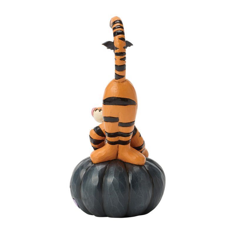 Een Tigger-figuurtje dat op een donkerblauwe pompoen staat met zwarte en oranje strepen.